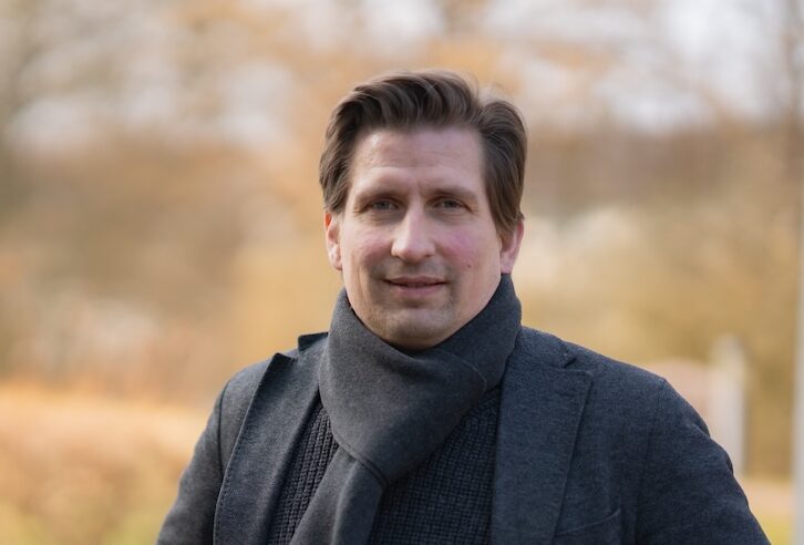 Julian Arends vor unscharfer Parklandschaft